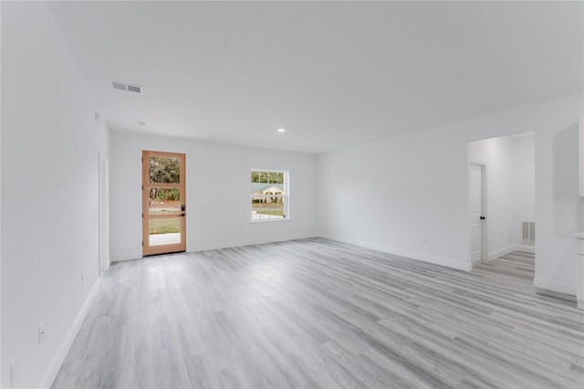 unfurnished living room featuring light wood-style floors, visible vents, and baseboards