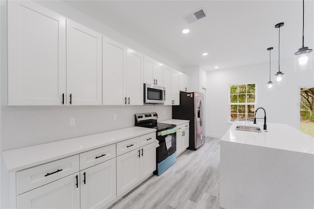 kitchen featuring visible vents, white cabinets, appliances with stainless steel finishes, decorative light fixtures, and a sink