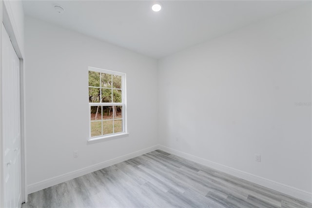 empty room featuring light wood-style floors, baseboards, and recessed lighting