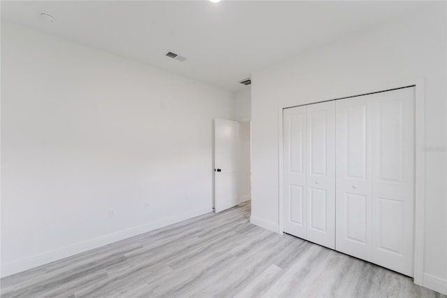 unfurnished bedroom with light wood-style floors, visible vents, baseboards, and a closet