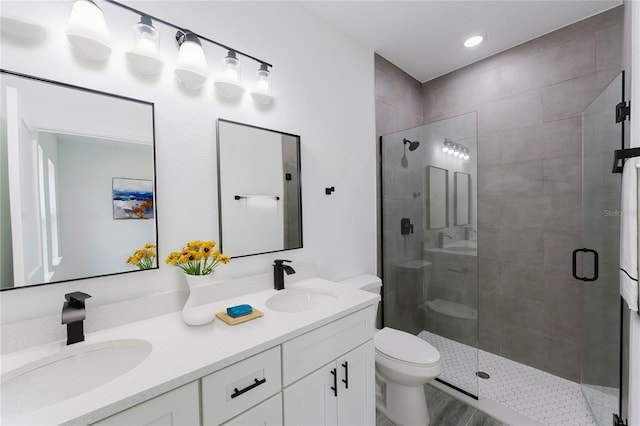 full bathroom featuring double vanity, a stall shower, a sink, and toilet