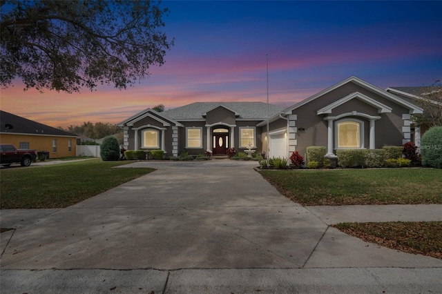 view of front of property with driveway, a yard, an attached garage, and stucco siding