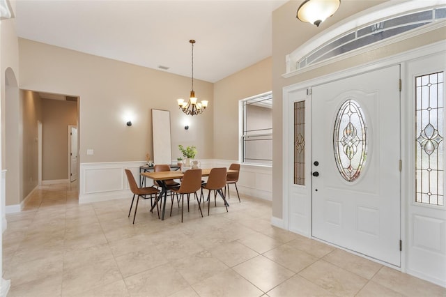 foyer entrance with arched walkways, a notable chandelier, a wainscoted wall, a decorative wall, and visible vents