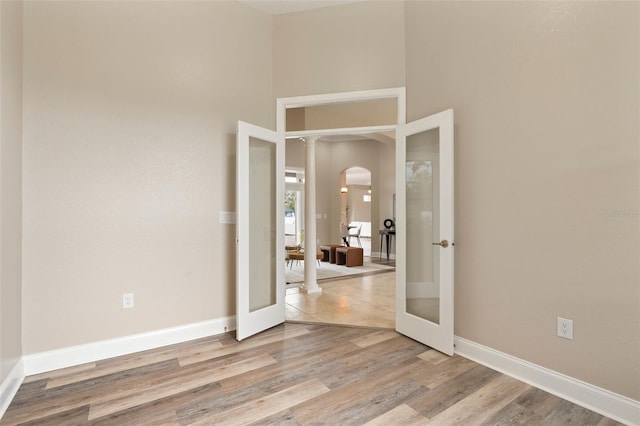 spare room with baseboards, arched walkways, wood finished floors, and french doors