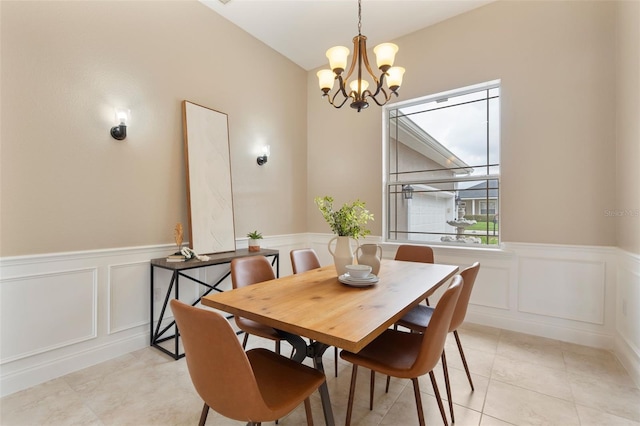 dining space with wainscoting, a decorative wall, an inviting chandelier, and light tile patterned floors