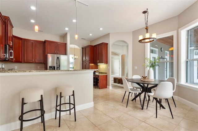 kitchen featuring stainless steel appliances, arched walkways, a notable chandelier, and a peninsula