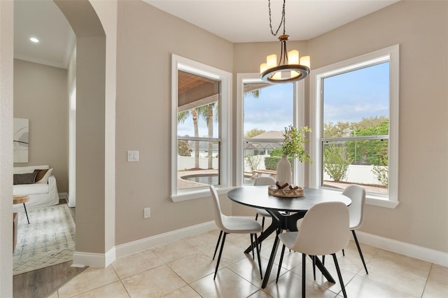 dining room featuring arched walkways, light tile patterned floors, recessed lighting, a chandelier, and baseboards