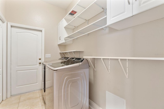 washroom featuring washing machine and dryer, cabinet space, visible vents, and light tile patterned floors