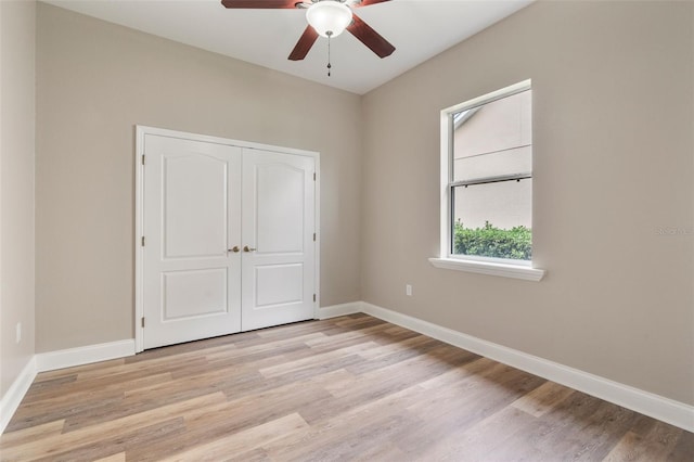 unfurnished bedroom with a ceiling fan, light wood-style flooring, baseboards, and a closet