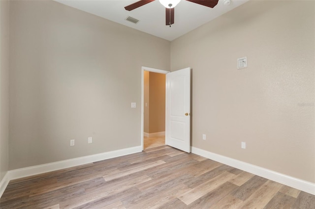 spare room featuring light wood-type flooring, visible vents, baseboards, and a ceiling fan