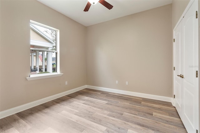 empty room with light wood finished floors, ceiling fan, and baseboards