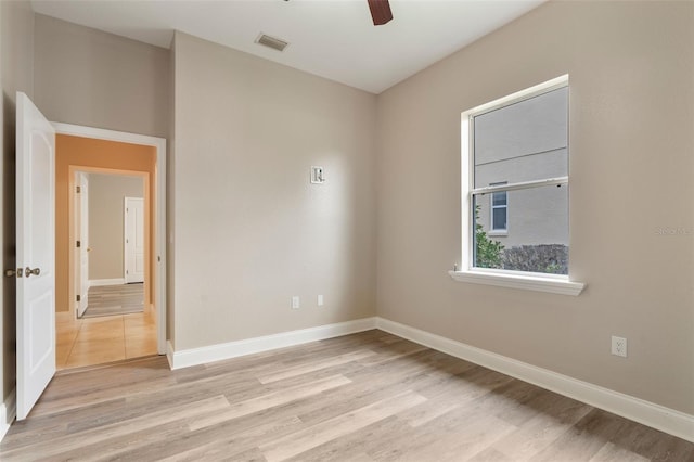 empty room featuring light wood-style floors, visible vents, ceiling fan, and baseboards