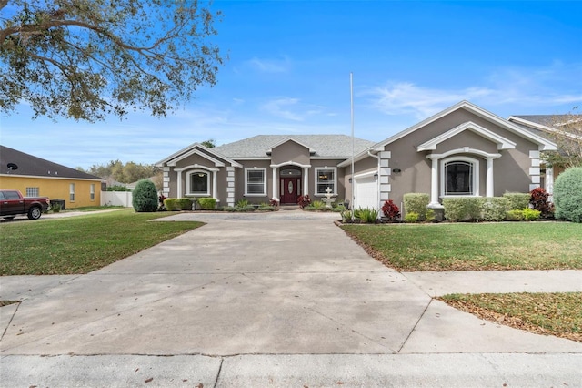 view of front facade with a garage, driveway, a front lawn, and stucco siding