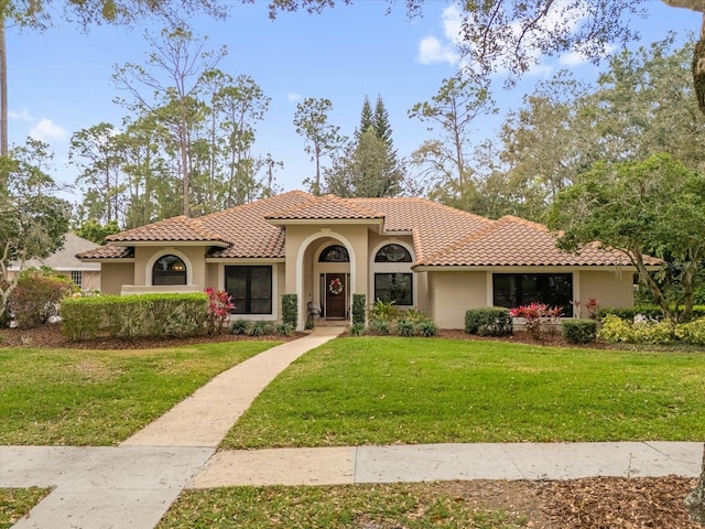 mediterranean / spanish home with stucco siding, a front lawn, and a tiled roof