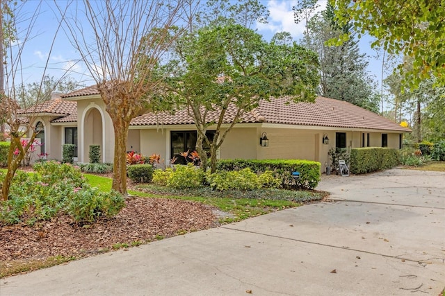 view of front of property with driveway, a tile roof, an attached garage, and stucco siding