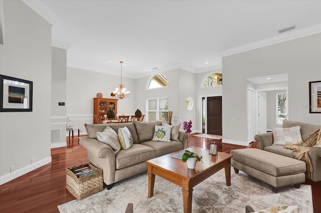 living room featuring a chandelier, baseboards, wood finished floors, and crown molding