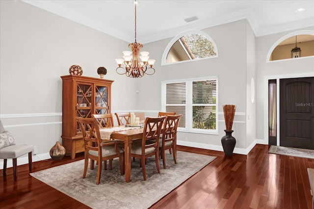 dining room featuring baseboards, visible vents, dark wood-style flooring, crown molding, and a notable chandelier