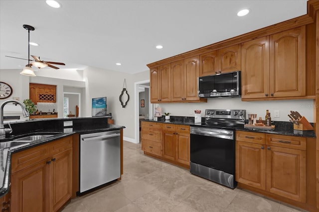 kitchen featuring recessed lighting, a sink, appliances with stainless steel finishes, dark stone counters, and brown cabinetry