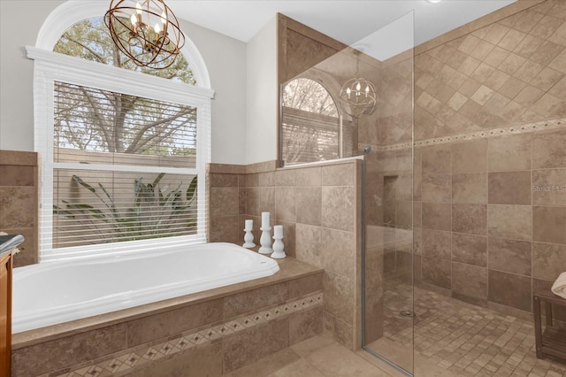 full bath featuring a bath, a stall shower, tile patterned flooring, and a notable chandelier