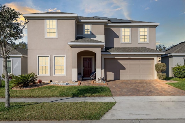 view of front of home with solar panels, decorative driveway, and stucco siding