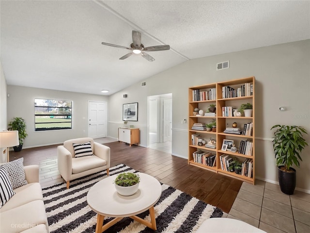 living room featuring wood-type flooring, lofted ceiling, ceiling fan, and a textured ceiling