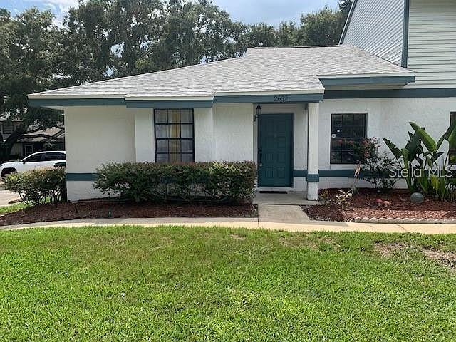 view of front of house with roof with shingles, a front lawn, and stucco siding