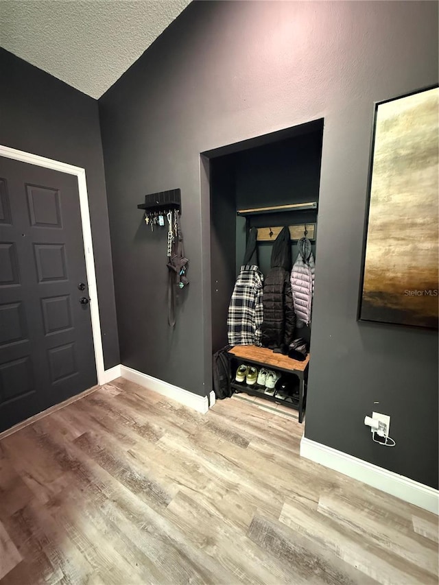 entryway with lofted ceiling, a textured ceiling, baseboards, and wood finished floors