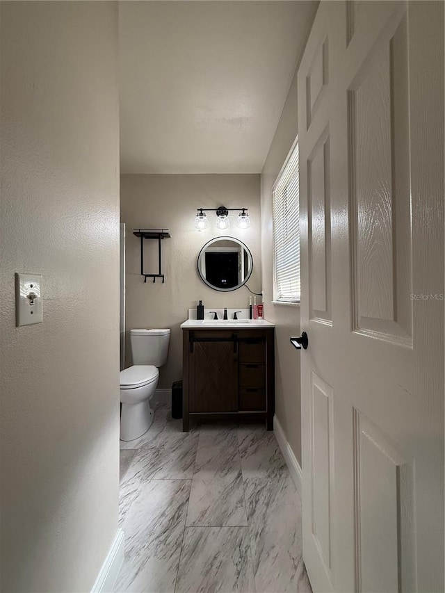 bathroom with marble finish floor, vanity, toilet, and baseboards