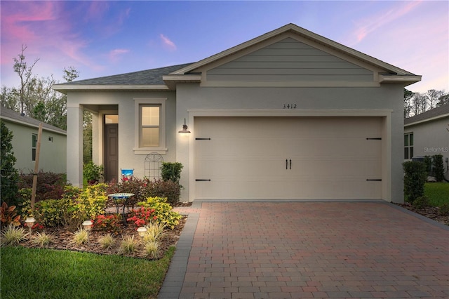 single story home with a shingled roof, decorative driveway, an attached garage, and stucco siding