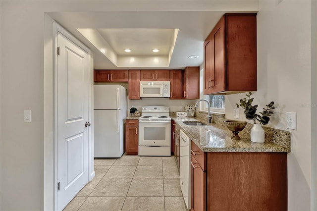 kitchen with light tile patterned floors, light stone counters, white appliances, a sink, and a raised ceiling