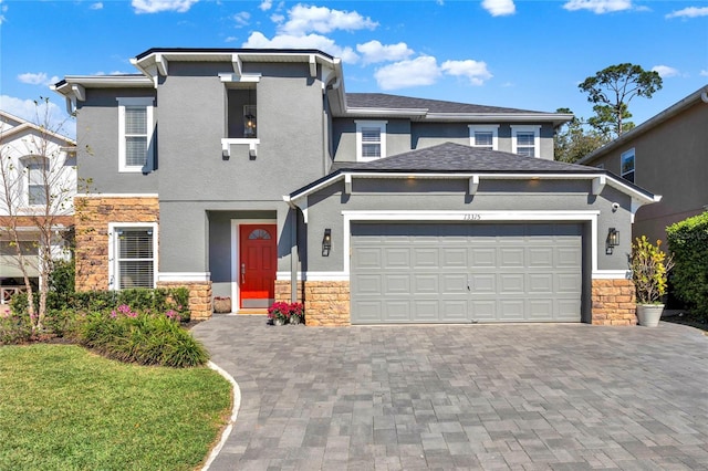 view of front of property with an attached garage, stone siding, decorative driveway, and stucco siding