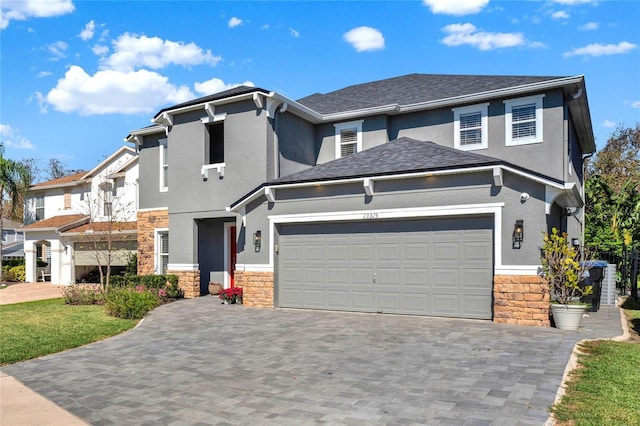 view of front of home featuring a garage, stone siding, decorative driveway, and stucco siding