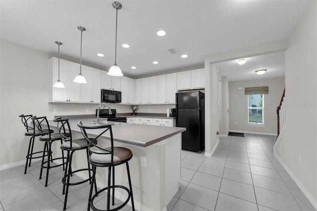 kitchen with dark countertops, a kitchen breakfast bar, decorative light fixtures, black appliances, and white cabinetry