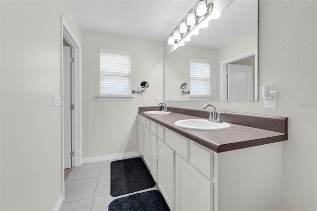 bathroom with double vanity, a sink, a textured ceiling, and tile patterned floors