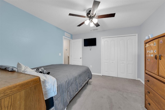 bedroom featuring light carpet, baseboards, visible vents, ceiling fan, and a closet