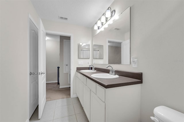 bathroom featuring a textured ceiling, tile patterned flooring, a sink, and visible vents