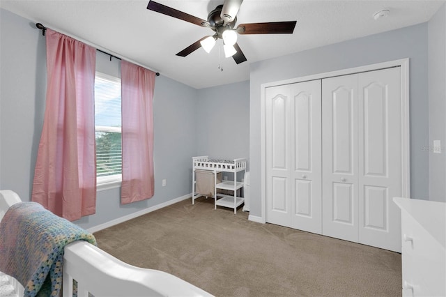 bedroom with baseboards, ceiling fan, a closet, and light colored carpet