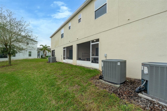 rear view of house with stucco siding, a yard, and central air condition unit