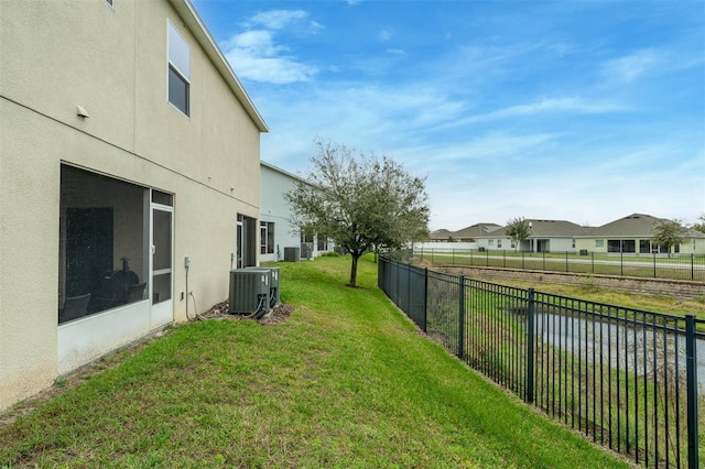 view of yard featuring a sunroom, central AC, a fenced backyard, and a residential view