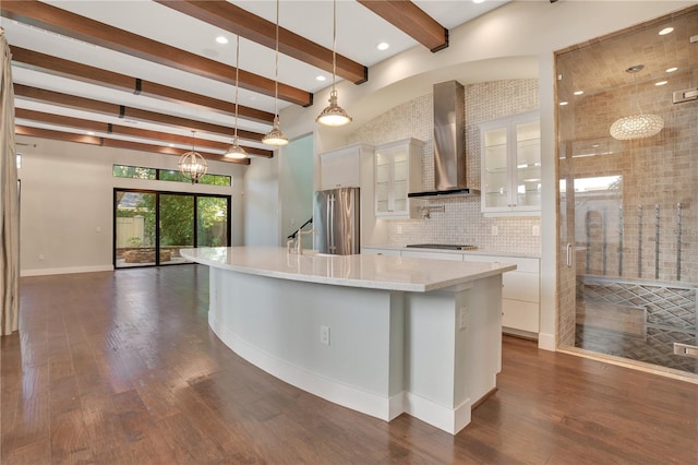 kitchen with pendant lighting, a spacious island, high quality fridge, wall chimney exhaust hood, and white cabinets