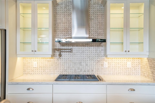 kitchen with tasteful backsplash, white cabinetry, wall chimney exhaust hood, and stainless steel gas stovetop