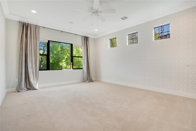 empty room with ceiling fan, crown molding, and light carpet