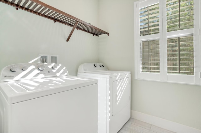 laundry area with independent washer and dryer, a healthy amount of sunlight, and light tile patterned floors