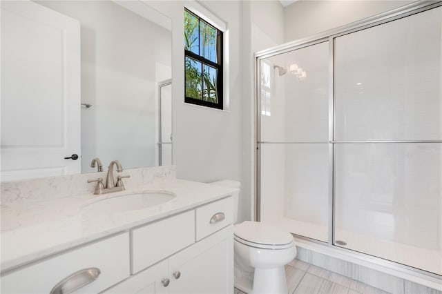 bathroom featuring toilet, a shower with shower door, and vanity