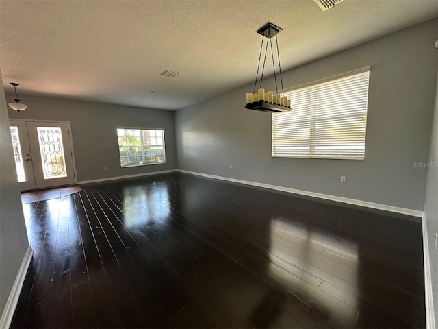 empty room featuring dark wood-type flooring, french doors, and a textured ceiling