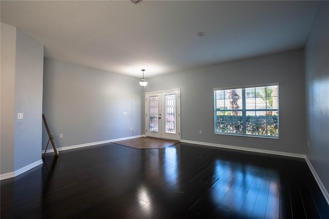 empty room featuring dark wood-type flooring, french doors, and baseboards