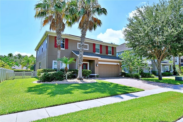 view of front of home with driveway, a garage, stucco siding, fence, and a front yard