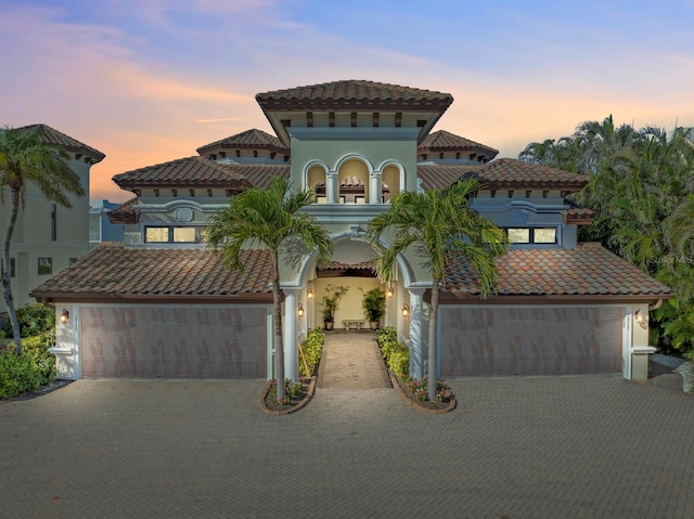 mediterranean / spanish-style home featuring a tiled roof, decorative driveway, and stucco siding