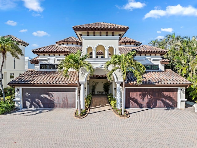 mediterranean / spanish house featuring a garage, decorative driveway, and a tile roof