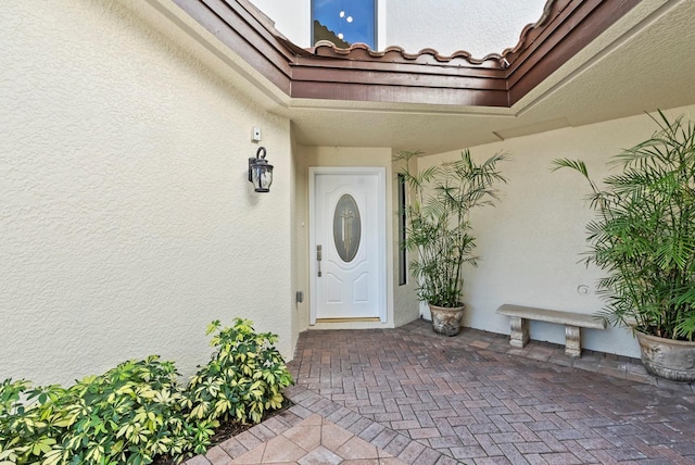 view of exterior entry with a tile roof and stucco siding